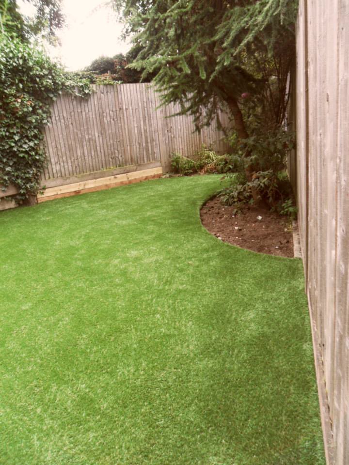 Synthetic turf laid up to a curved garden bed